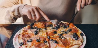 A woman practicing intuitive eating while eating pizza