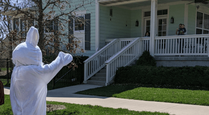 The easter bunny waves to a house and family