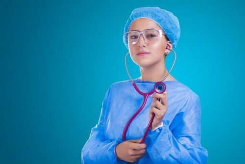 Image: female doctor in scrubs, holding stethoscope
